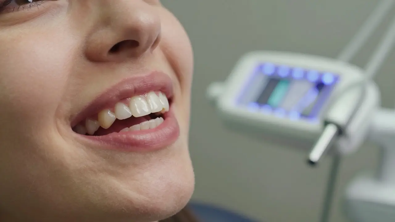 Nerovnoměrně osvětlené zuby po použití bělicích pásek s červenými dásněmi a zrcadlem odhalujícím dentální vybavení.